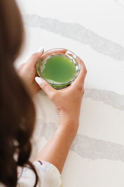 Abby Manawes' hands holding a glass of green celery juice