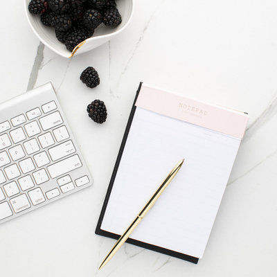 Photo of a notebook and pen next to a keyboard.