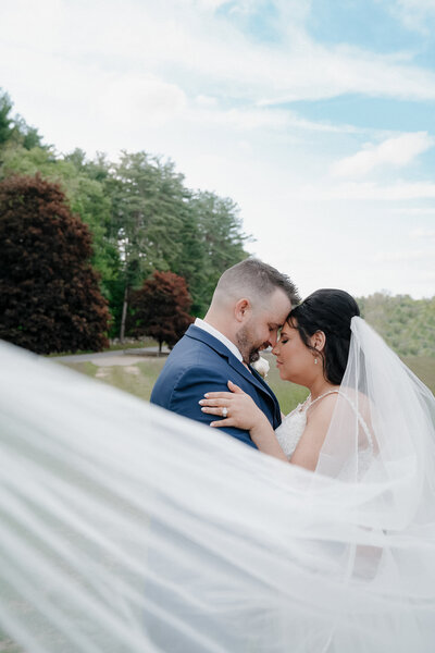 A tender moment captured as a newlywed couple stands close, their heads touching in an affectionate embrace, exuding romance and intimacy on their wedding day.
