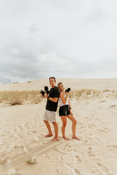 Male and Female Videographer pose with cameras