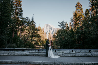 Bride and groom walk hand in hand along a forest trail surrounded by towering pine trees during their Lake Tahoe elopement.