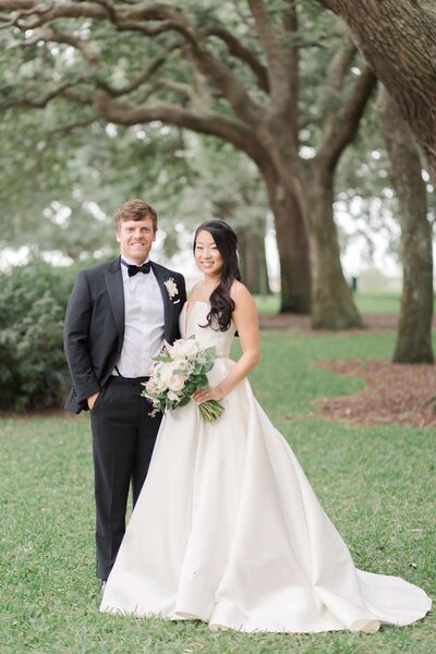 bride and groom smiling under willow trees