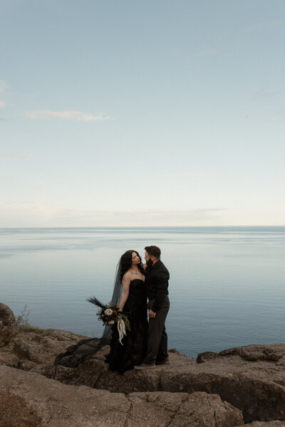couple sharing a celebratory kiss by a river during an intimate outdoor elopement in early spring