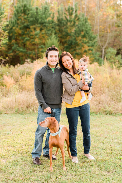 Family with a baby girl and a visla posing for a photo during their fall photos in Raleigh NC. Photographed by Raleigh family photographers A.J. Dunlap Photography.