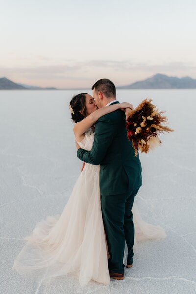 Couple kiss in their wedding clothes on the Bonneville Salt Flats