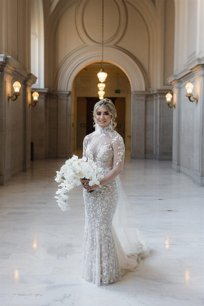 Bride in lace gown holding white orchid bouquet