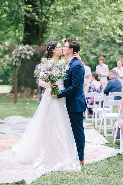 Bride and groom kiss coming down the aisle during wedding ceremony at the stables at strawberry creek in knoxville, tennessee