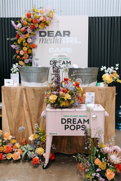Corporate event decor for Dream Pops booth with playful florals and product styling, curated by Bloom Bar for Dear Media IRL.