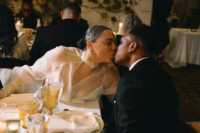 Bride and groom kissing at table during their wedding reception in Philadelphia