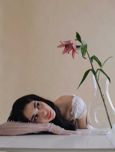 Model posing with flower in vase in photo studio taken in albuqerque new mexico.