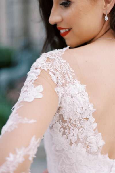 detail shot of bride in her lace wedding dress looking over her shoulder, photo highlighting the lace of the back of the dress and arm