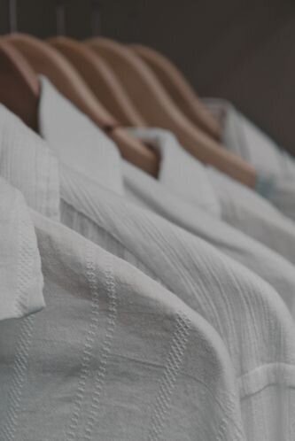 organized closet with a row of white shirts hanging on wood hangers