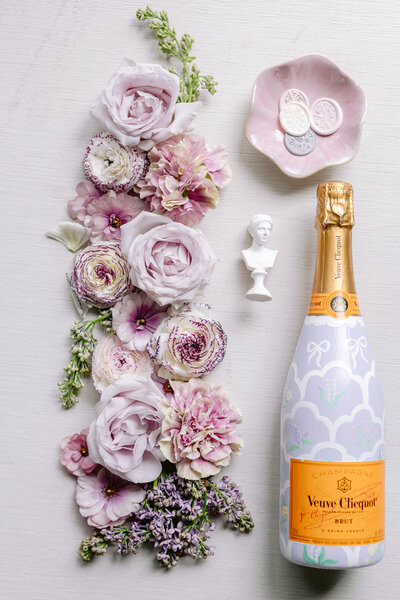 A bottle of Brut Champagne  sits between wedding shoes