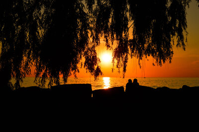 A couple sits on a rock, enjoying a vibrant sunset in Northeast Ohio.