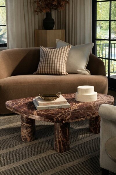 A cozy living room featuring a comfortable couch, a stylish coffee table, and a bright window allowing natural light in.