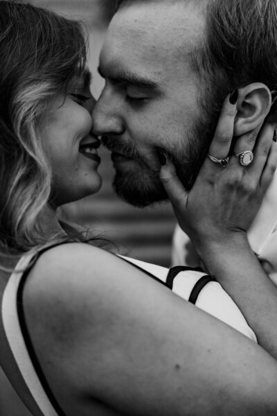 Black and white close-up of couple smiling at each other outside the Shelby County Courthouse in Memphis, woman’s hands on fiancé’s face.