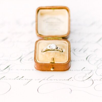 A leather ringbox on top of calligraphy invites for a Maui elopement
