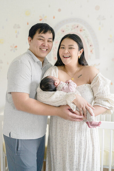 A new father holds his newborn daughter, who is yawning.