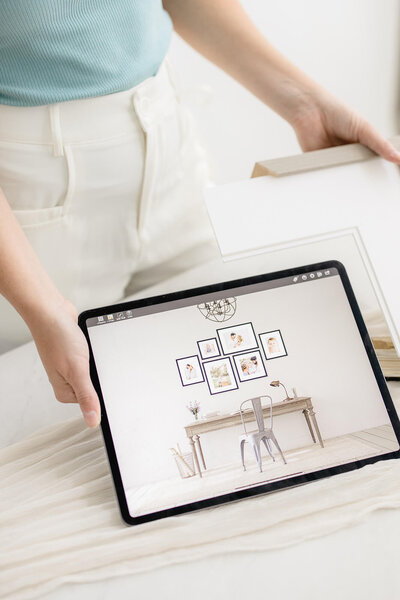 photographer showcasing custom designed gallery wall on ipad in oklahoma city all white studio for an okc nichols hills home
