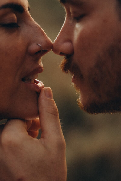 Couple holding just about to kiss, the husband in pulling her lip down. Captured by a noosa photographer