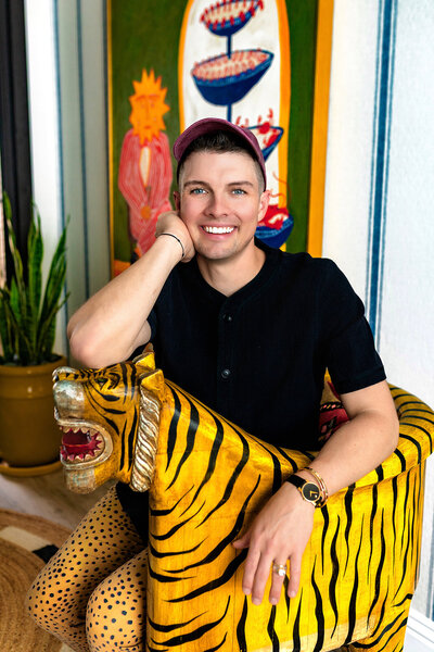Cave Creek real estate agent sitting in a colorful room with striped wallpaper, a tiger chair, and a large colorful painting. 