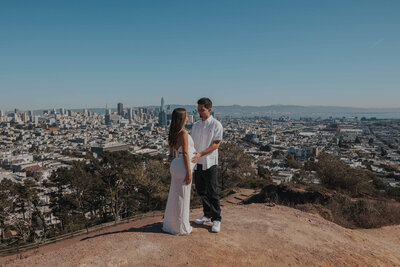 Expecting couple poses at the top of Corona Heights in San Francisco, California.