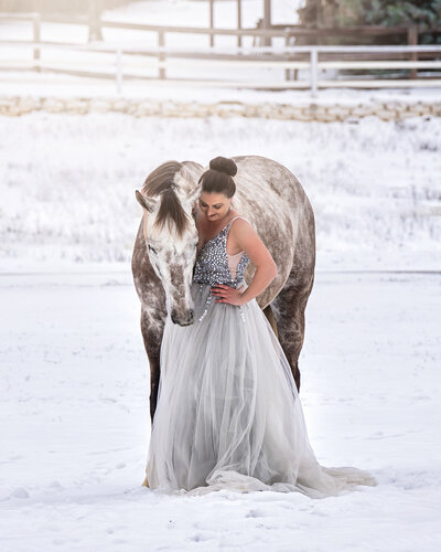 Dallas pet photographer wearing a silver ballgown in the snow with her gray horse.