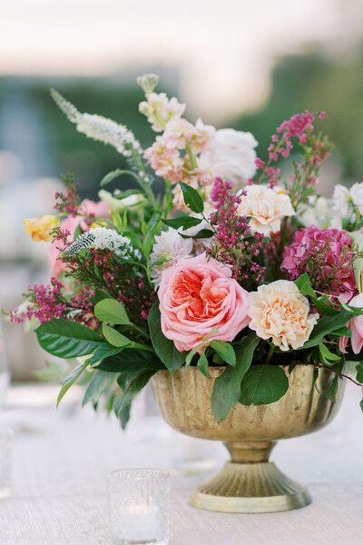 Close up of pink and white floral arrangement with greenery in a gold vase