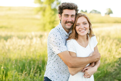 A white couple hugging and smiling at the camera.