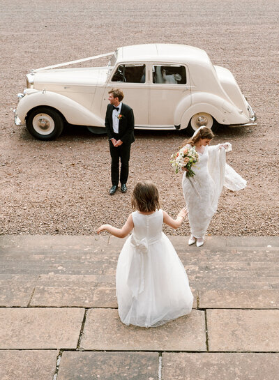 bride and groom playing on steps with flowergirl