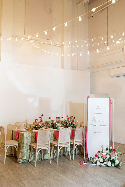 Custom linen banner welcome sign with pink ribbons tied on each side integrated with whimsical floral wedding display