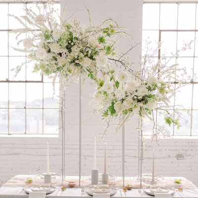 Two large elevated table centrepieces of white airy flowers on a table at a L'Eloi wedding. 