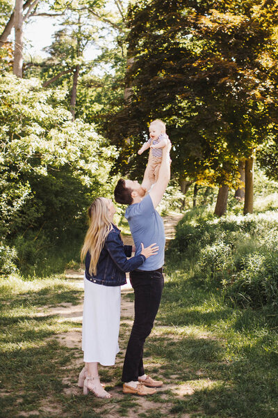 Dad throwing baby boy up in air while mom looks on