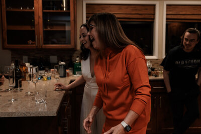 Bride and her new mother-in-law laughing in the cabin kitchen as dinner is prepared for them in Portland, Oregon. 