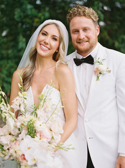 A Nashville bride smiling while holding a beautiful bouquet next to the groom