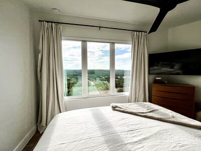 Bed with white covers facing large windows