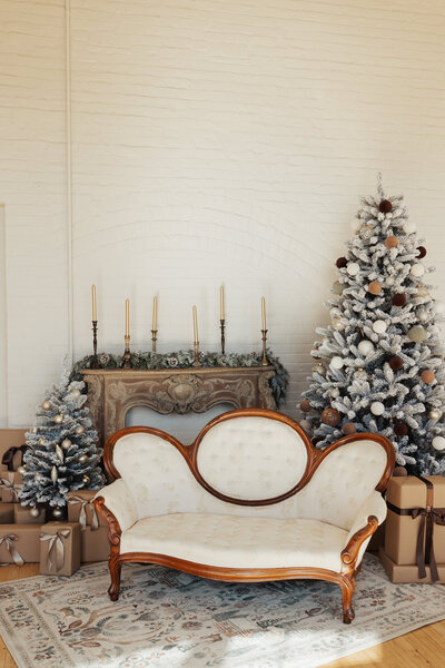 Vintage cream couch in front of a fireplace mantle and Christmas tree display at The Archer Atelier
