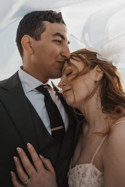 Wedding couple embracing under a veil in Norway