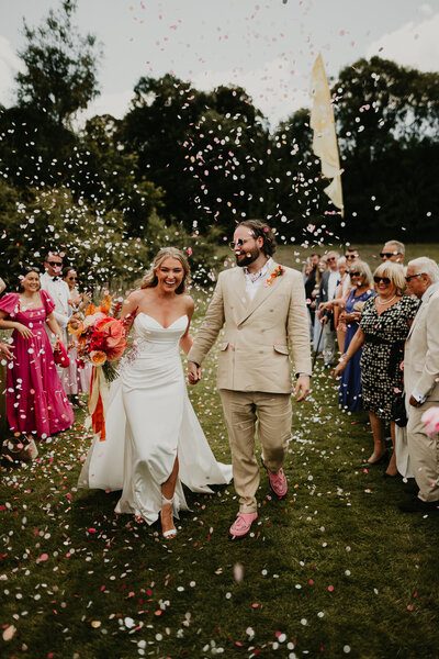 Bride and Groom walk through confetti tunnel at Hadsham Farm. 