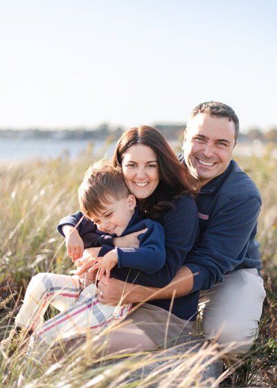 family sitting in the tall grass at a beach having fun