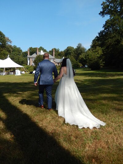 A bride and groom holding hands and walking away from the camera
