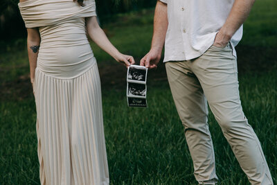 husband and wife holding ultrasound photo of their baby