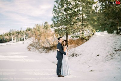 Engaged couple pose by embracing each other in the snow at Snow Summit