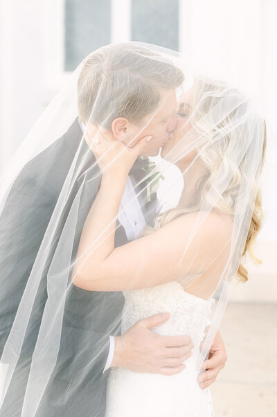 bride and groom kissing in veil