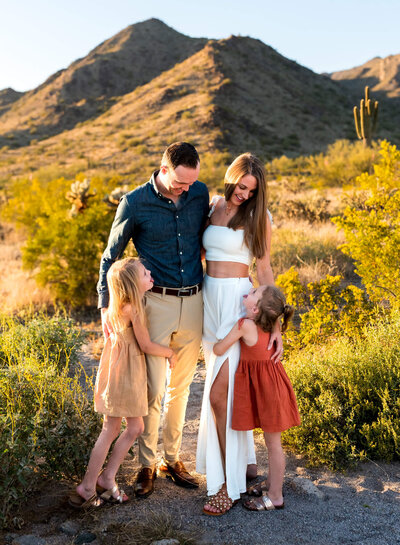 Family smiling at each other at sunset in the desert mountains of Phoenix