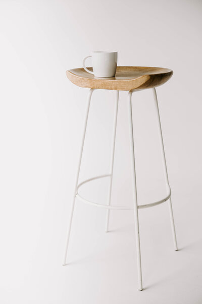 White coffee mug sitting on top of a wooden stool