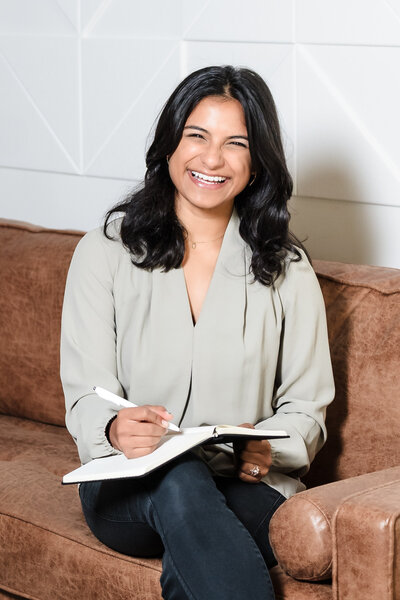woman posing in a couch with a notebook on her lap