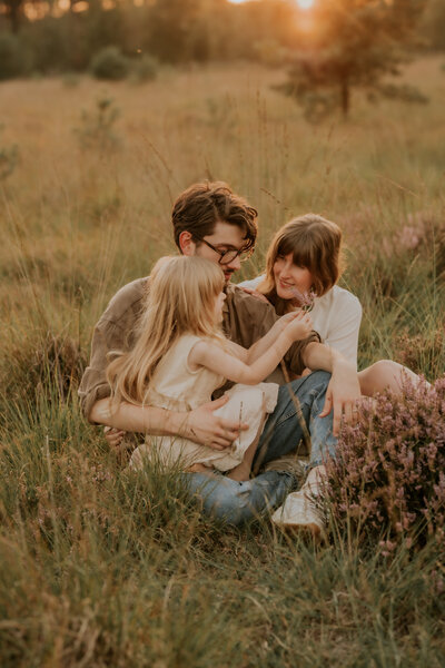 Gezin poseert in grasveld tijdens zonsondergang voor familie fotoshoot