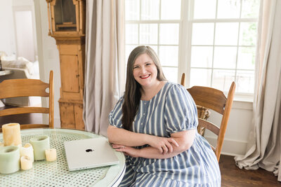 Lauren sits at her breakfast nook table in blue and white striped dress
