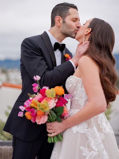 bride and groom shares a kiss while bride holds a bouquet